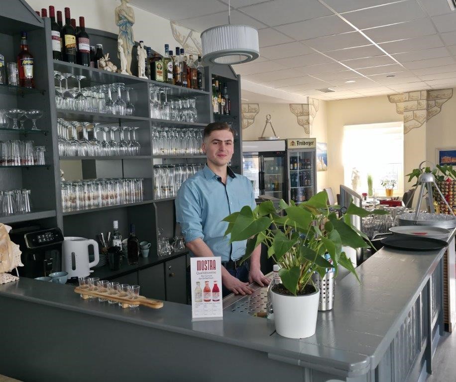 Servicekraft serviert Speisen an einem Tisch mit Gästen